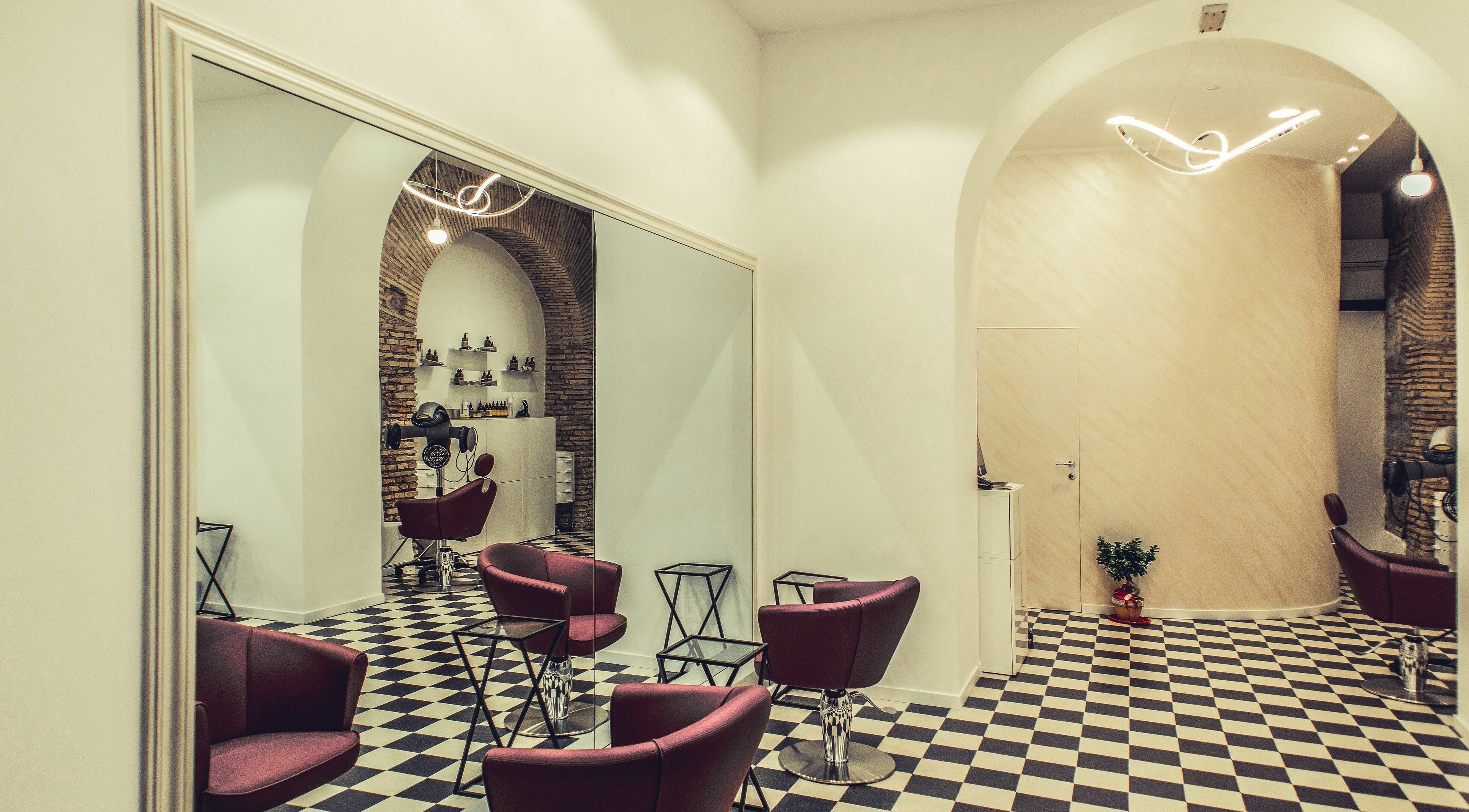 Interno elegante di Grazia Bianchi Hair Spa Couture a Roma, Lazio, IT con poltrone rosse e decorazioni moderne.
