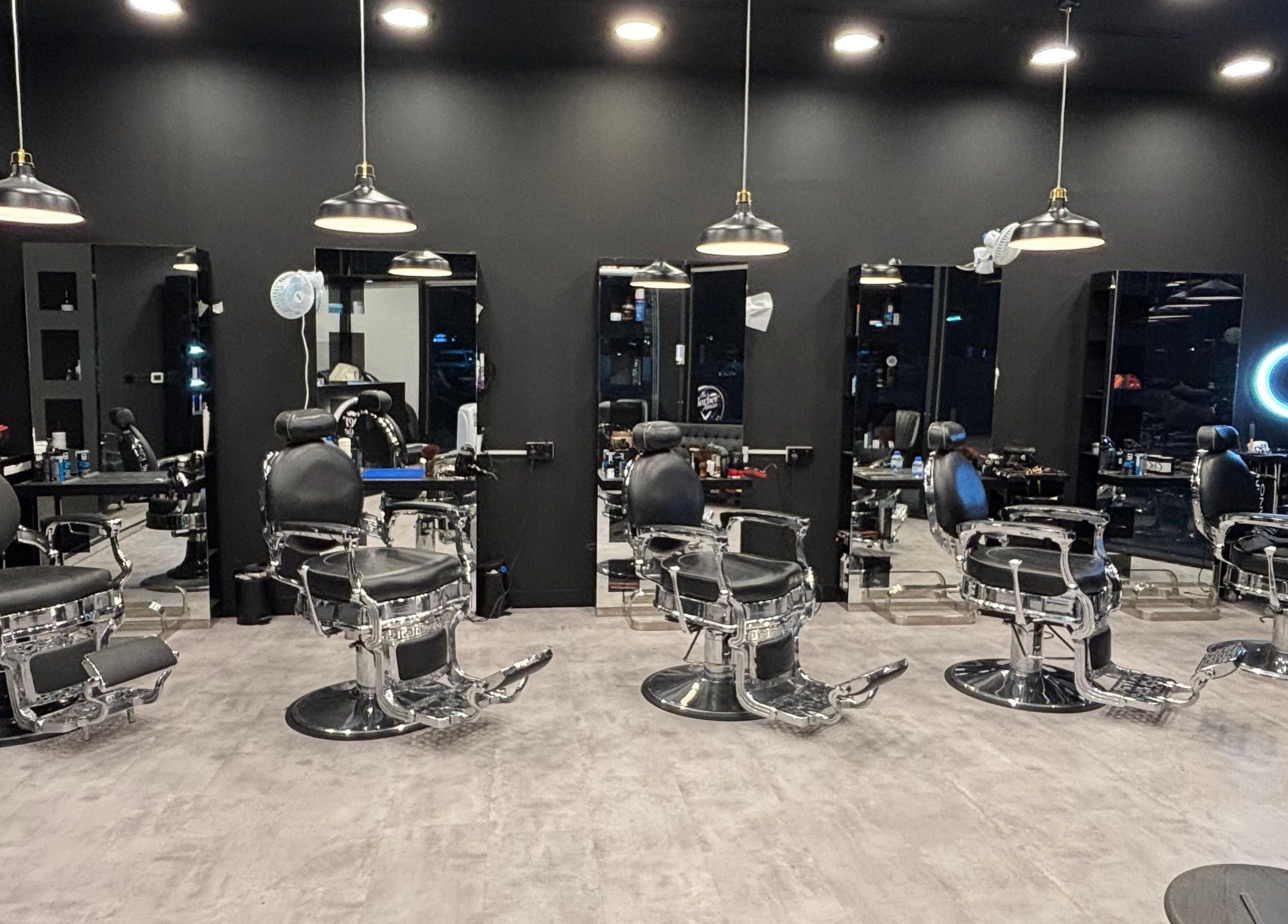 Modern barber chairs at The Barber House - JLT, Dubai, Dubai, AE with sleek black interiors.