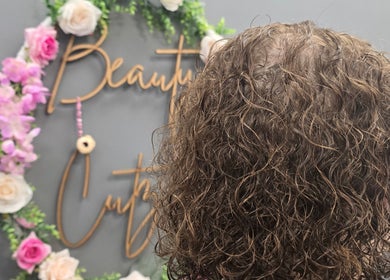 Curly hair styled beautifully at Beauty Cutz, Telford, England, GB, with floral decor in the background.