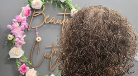 Curly hair styled beautifully at Beauty Cutz, Telford, England, GB, with floral decor in the background.