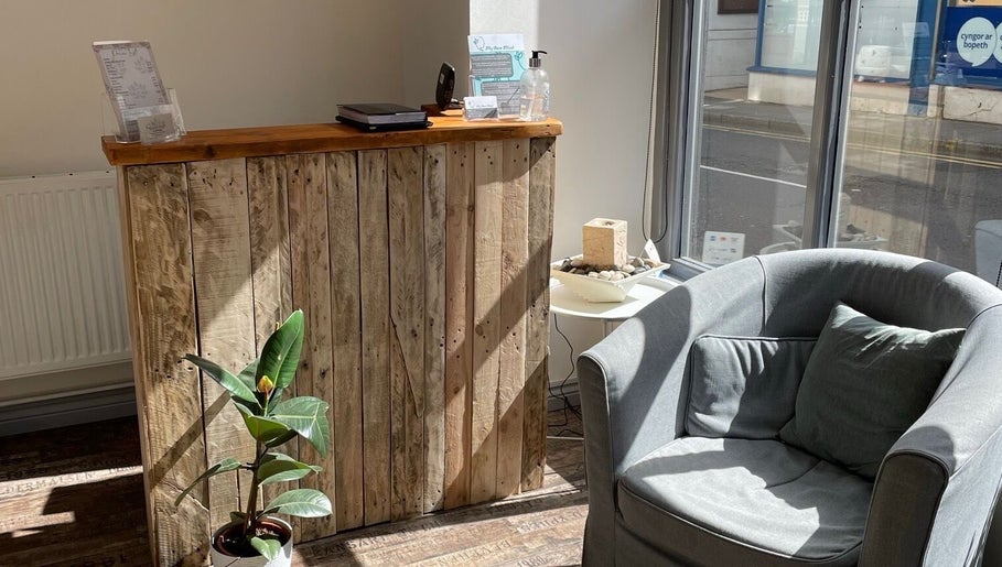 Welcoming reception area at In-Touch Therapies by Frances, Pontypool, Wales, GB, with wooden desk and plush chair.