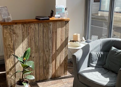 Welcoming reception area at In-Touch Therapies by Frances, Pontypool, Wales, GB, with wooden desk and plush chair.