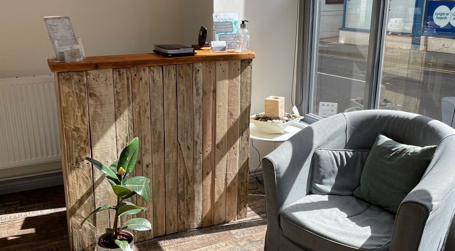 Cozy reception at In-Touch Therapies by Frances, Pontypool, Wales, GB with wooden decor and armchair.