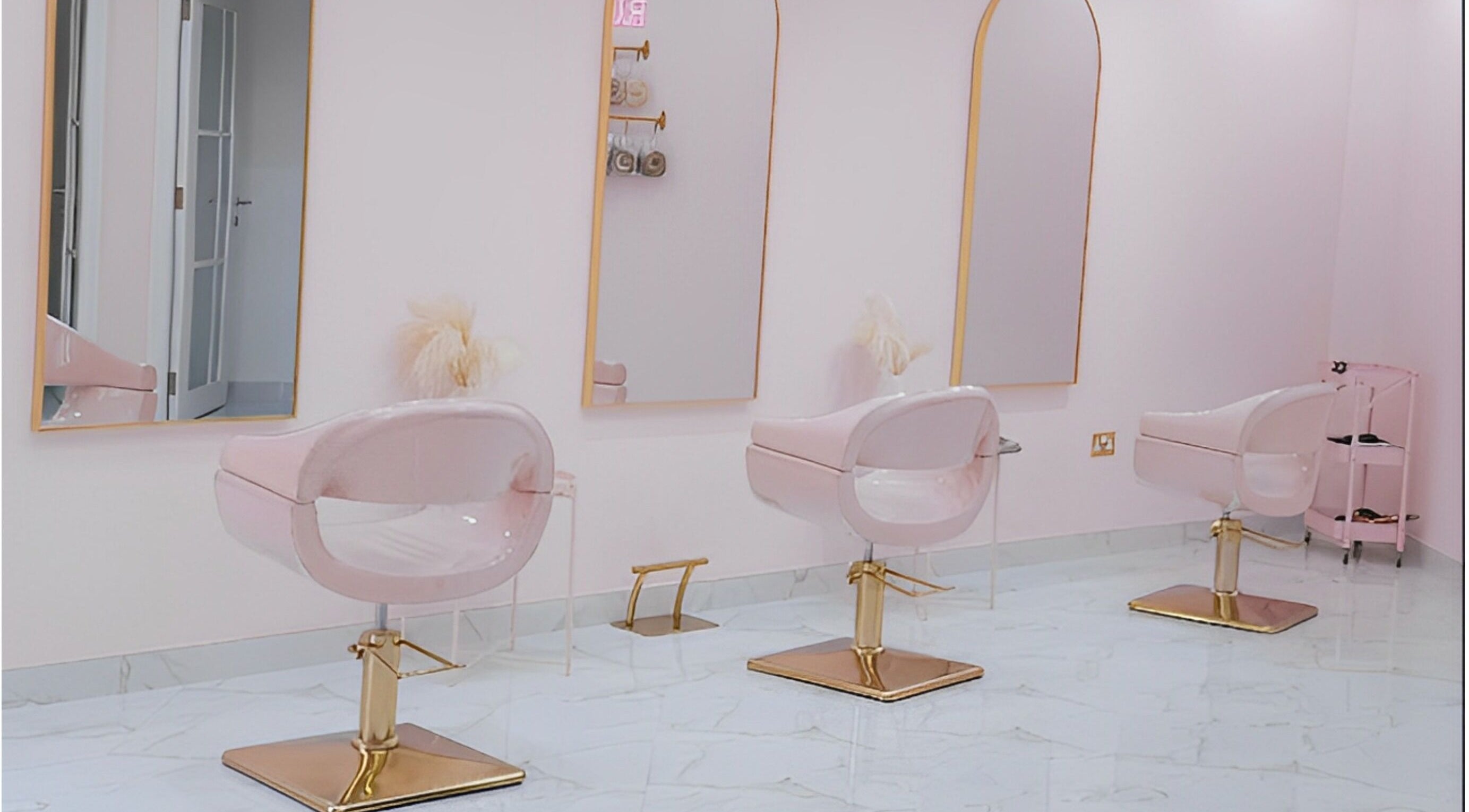 Chic styling area at The British Salon JLT, Dubai, Dubai, AE featuring stylish pink and gold salon chairs.
