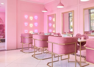 Chic pink interior of BOA Beauty Bar Sea Point, Cape Town, Western Cape, ZA with plush seating and heart neon lights.