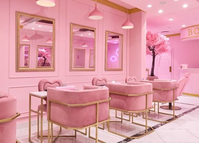 Chic interior of BOA Beauty Bar Rondebosch, Cape Town in pink decor with plush seating and mirrors.
