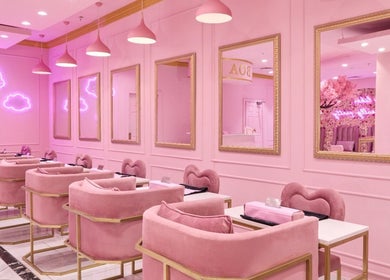Chic pink interior of BOA Beauty Bar Rondebosch in Cape Town, Western Cape, ZA with neon clouds and plush seating.