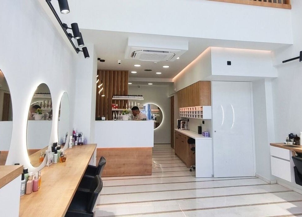 Κομψό εσωτερικό σαλόνι ομορφιάς Strataras, Ηράκλειο, GR με φωτισμένα καθρέφτες και ξύλινα έπιπλα.