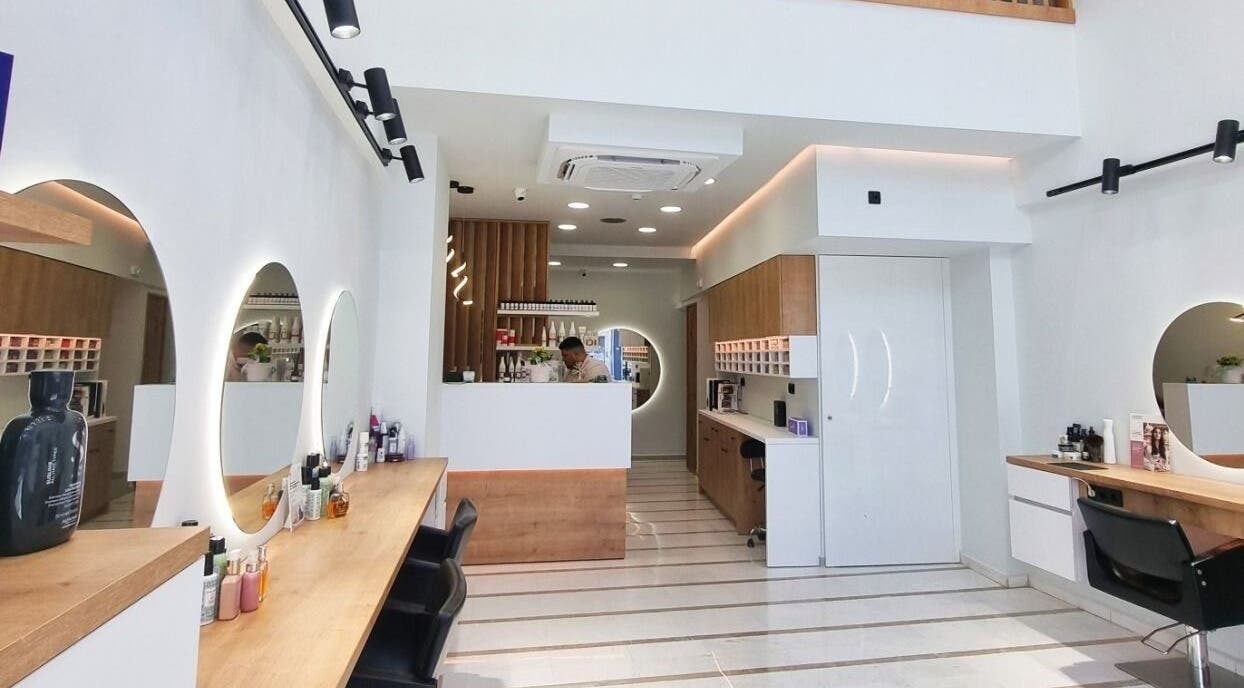 Κομψό εσωτερικό σαλόνι ομορφιάς Strataras, Ηράκλειο, GR με φωτισμένα καθρέφτες και ξύλινα έπιπλα.