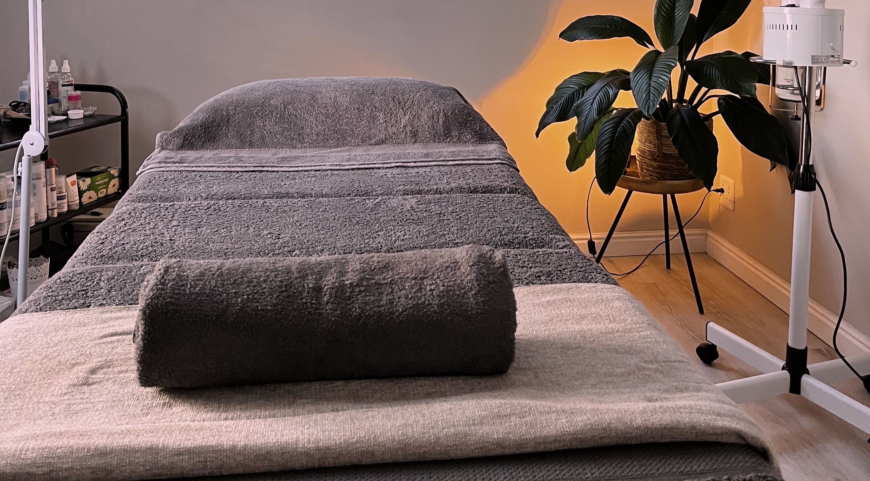 A calming massage room at Wellness by Zo, Cape Town, Western Cape, ZA with grey linens and warm lighting.