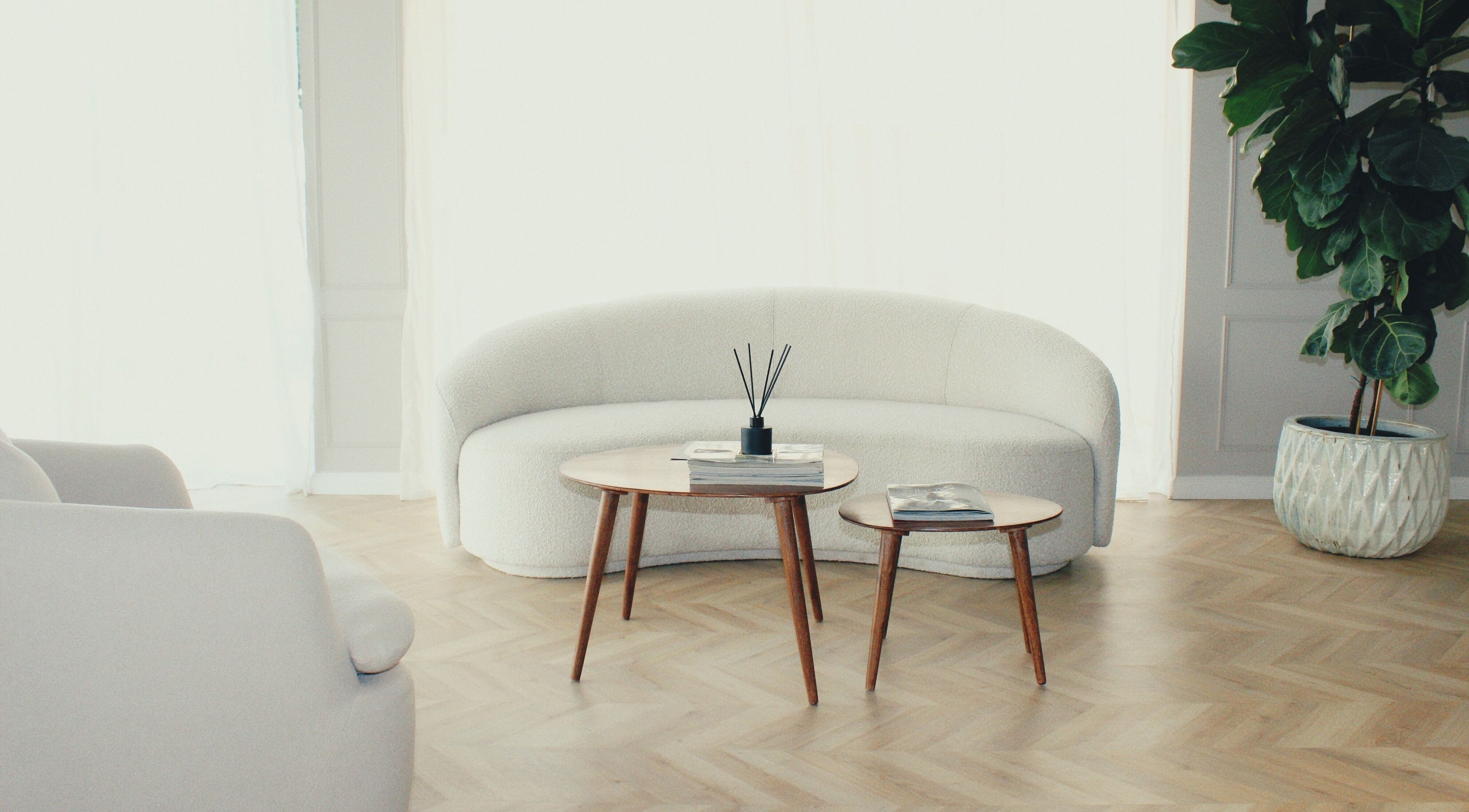 Elegant seating area at Skincode Beauty Lounge, Nicosia, CY with a plush sofa, wooden tables, and a potted plant.