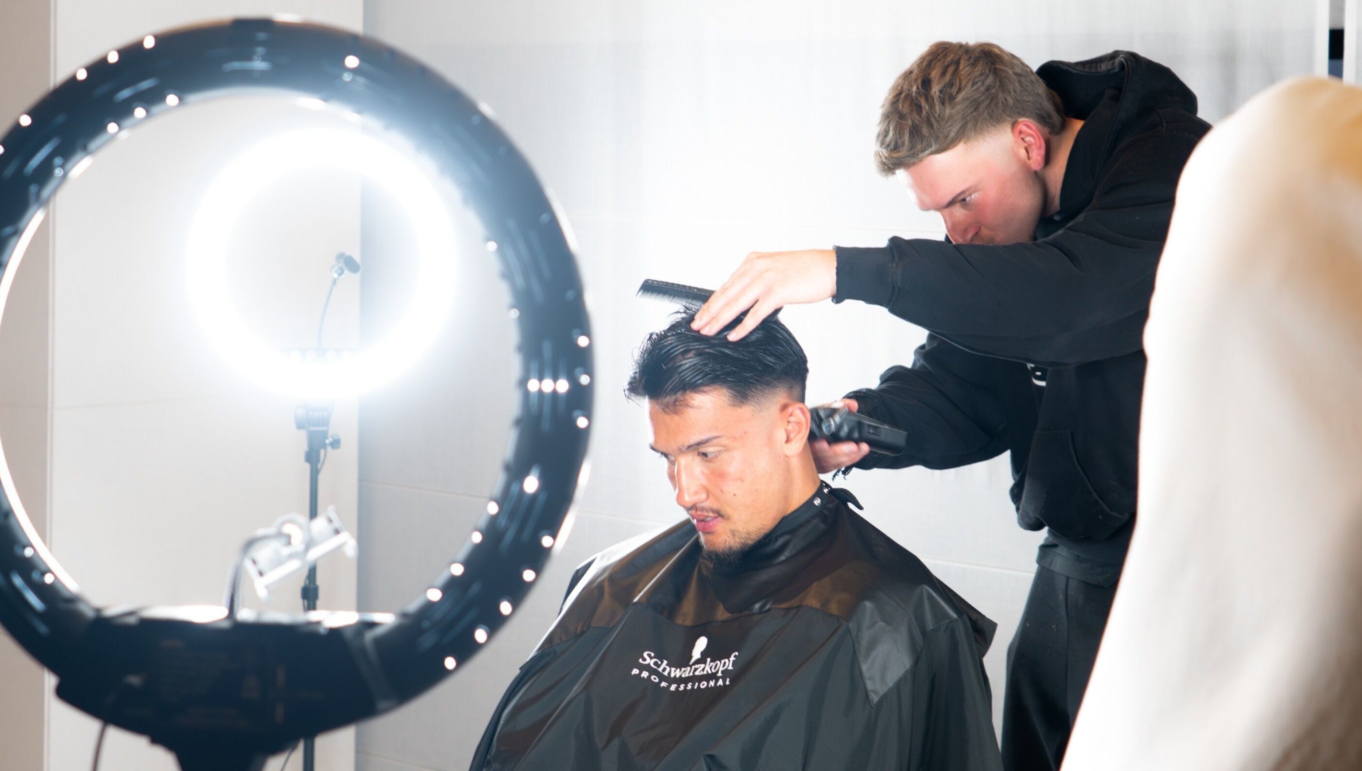 Stylist at FLETCHCUTZ in Woodvale, Western Australia, AU expertly cutting a client's hair under bright salon lights.