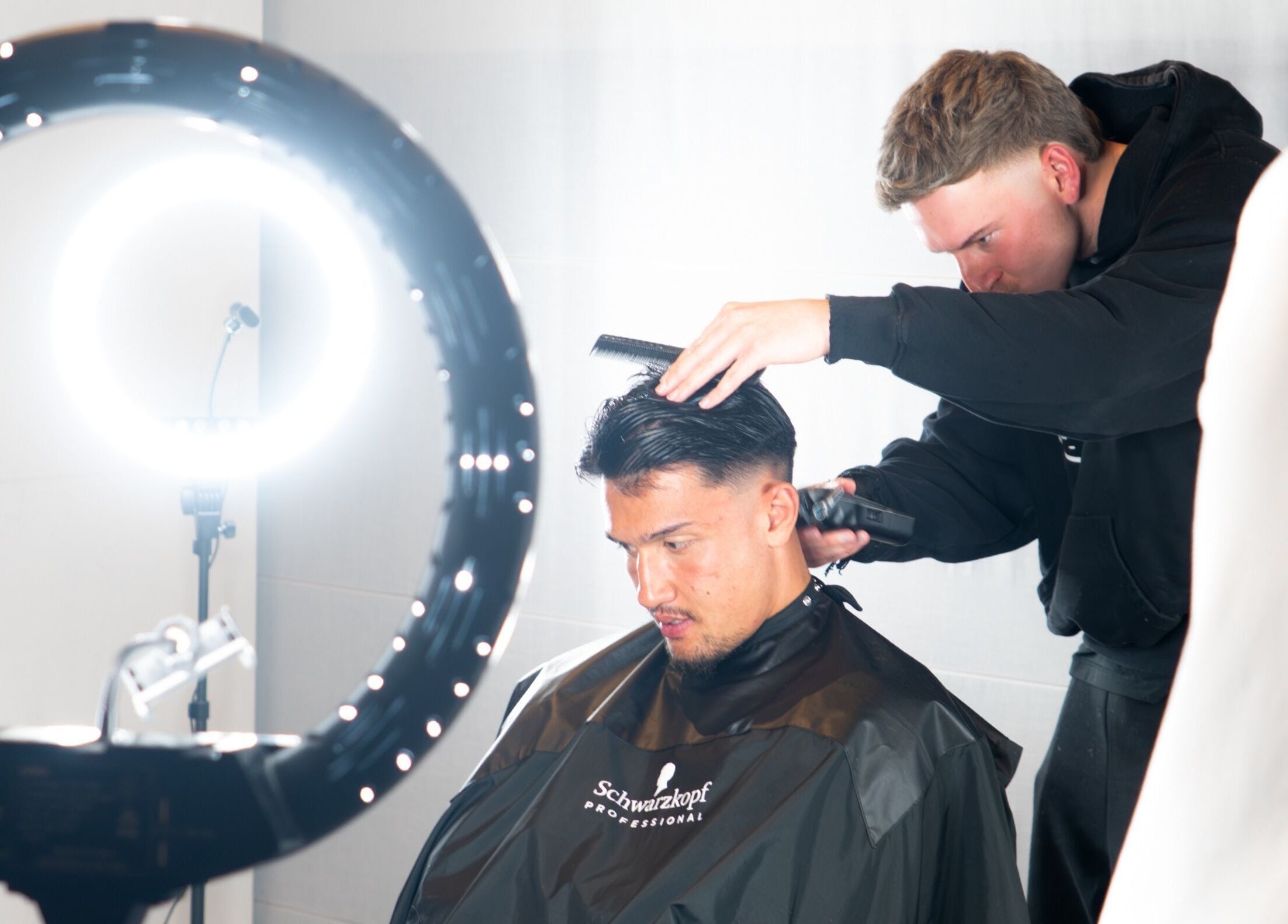 Stylist at FLETCHCUTZ in Woodvale, Western Australia, AU expertly cutting a client's hair under bright salon lights.