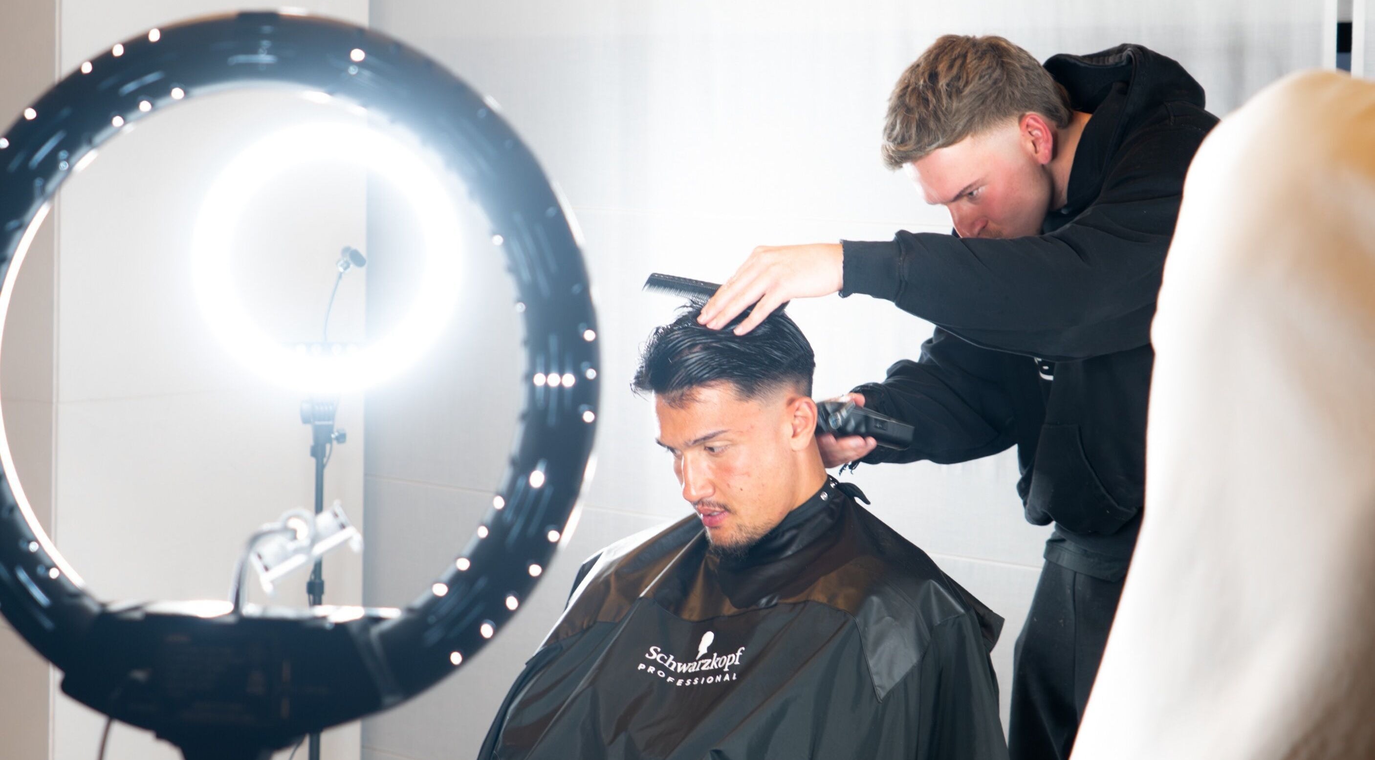 Stylist at FLETCHCUTZ in Woodvale, Western Australia, AU expertly cutting a client's hair under bright salon lights.
