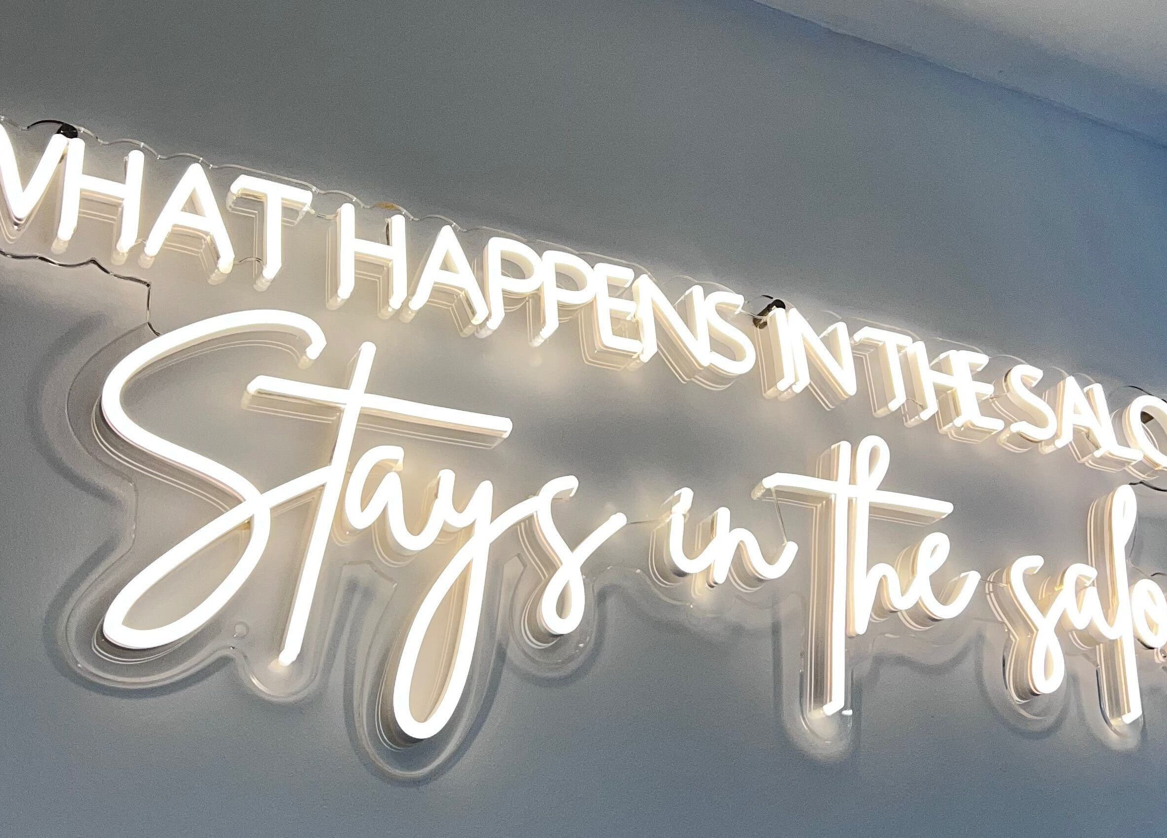 Neon sign saying 'What happens in the salon stays in the salon' at Infinity Hair, Littleport, England, GB.