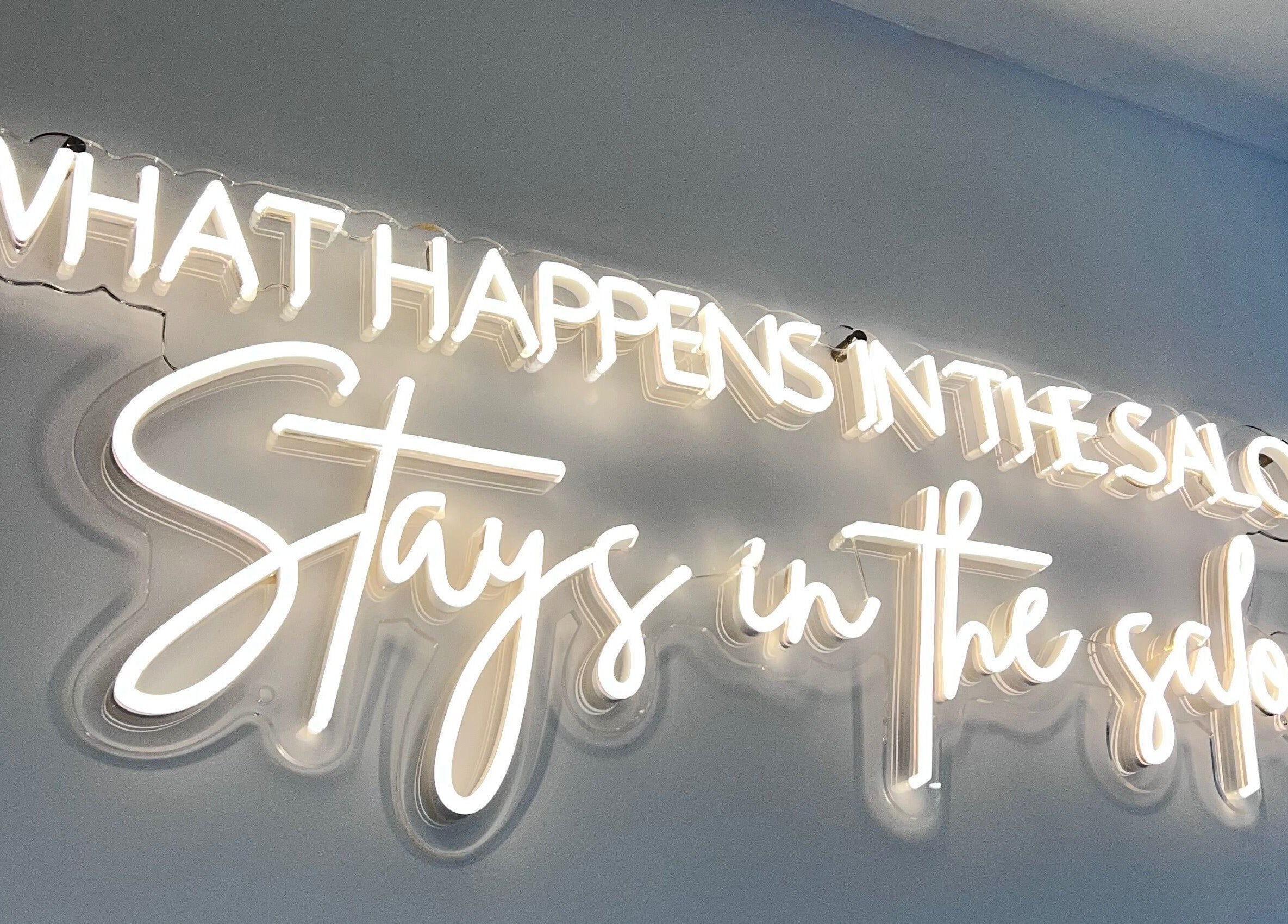 Neon sign saying 'What happens in the salon stays in the salon' at Infinity Hair, Littleport, England, GB.