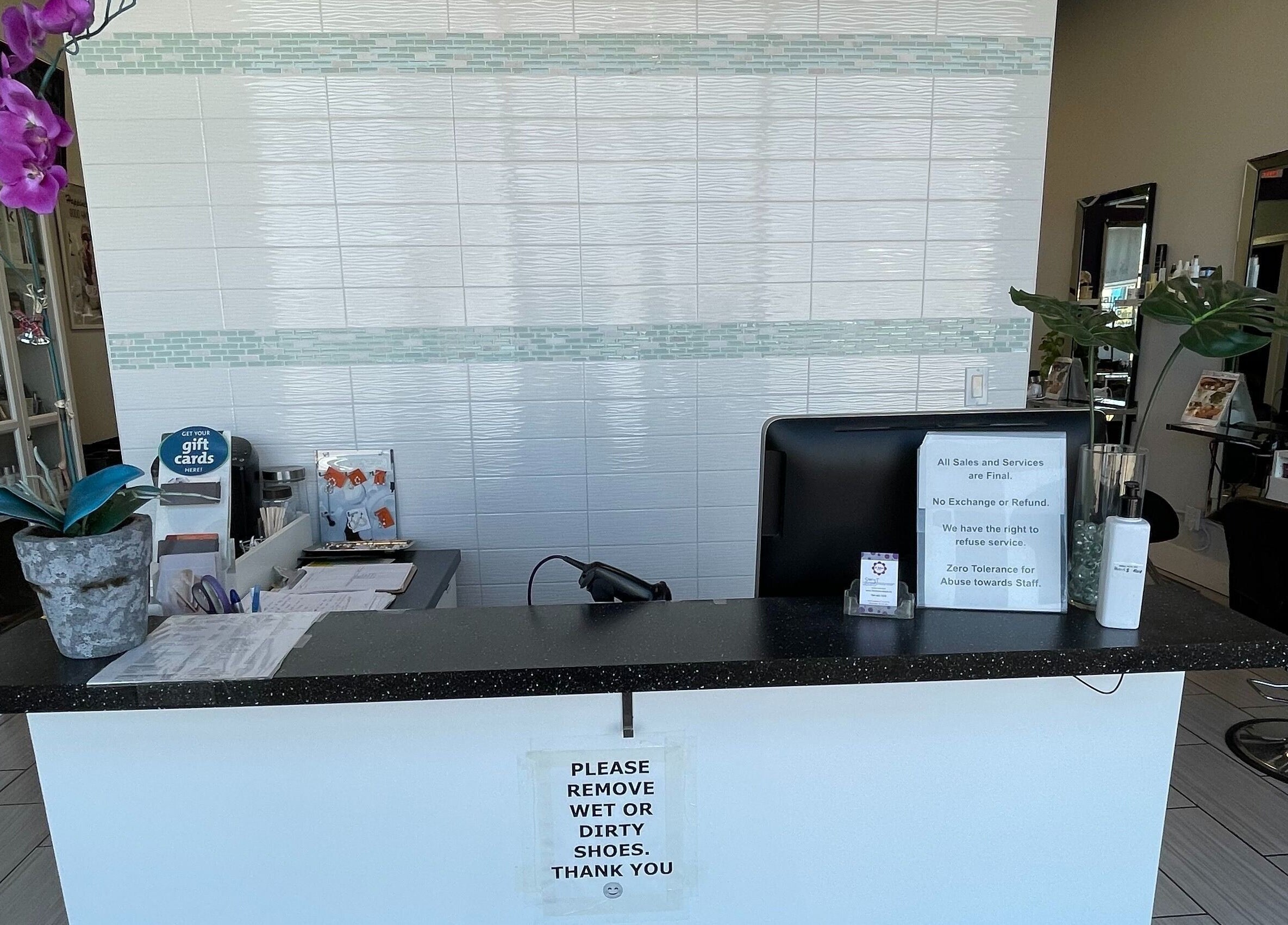 Reception desk at Si Salon and Spa, Edmonton, Alberta, CA with orchids showcasing a clean, inviting environment.