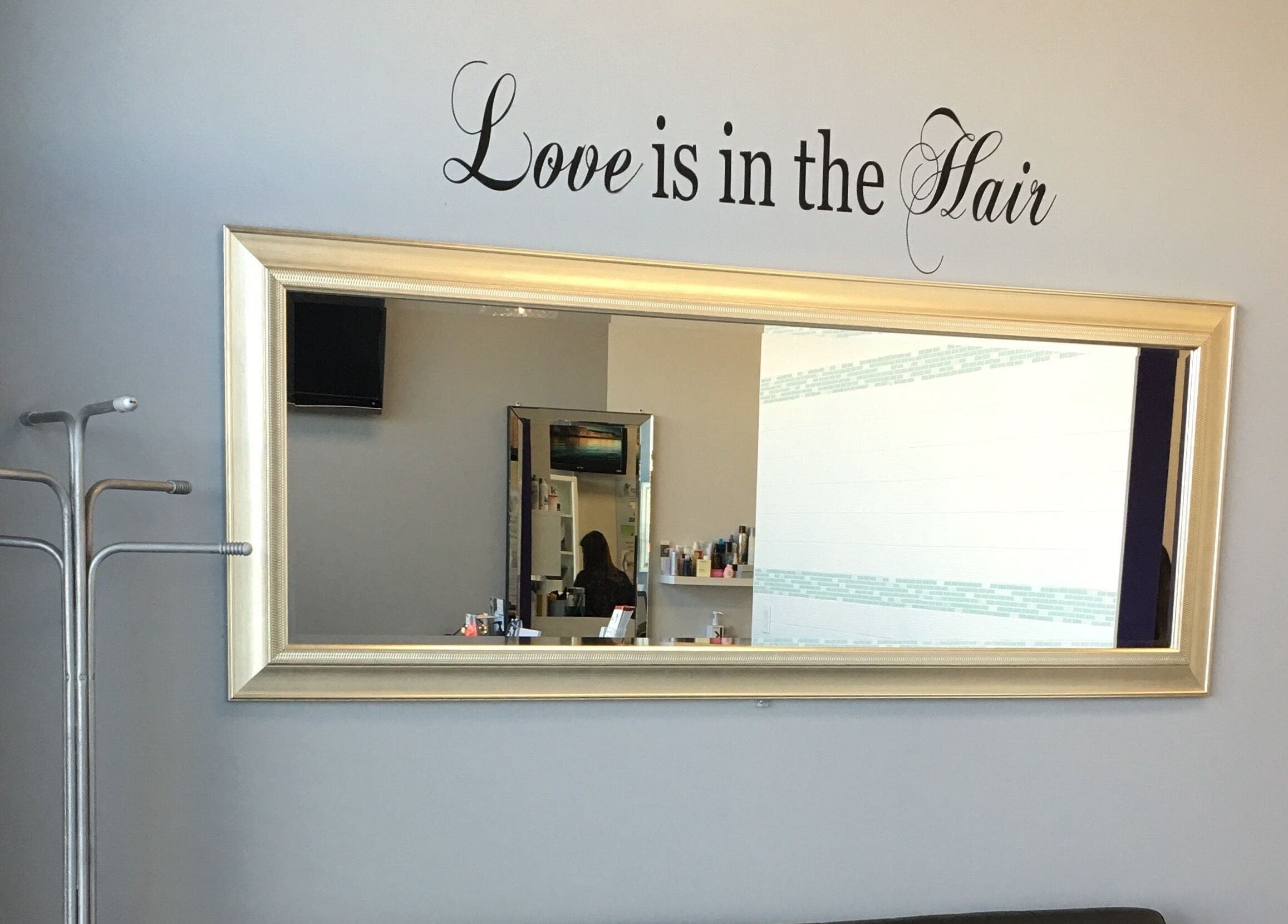 Elegant wall mirror at Si Salon and Spa in Edmonton, Alberta, CA with a 'Love is in the Hair' decal.