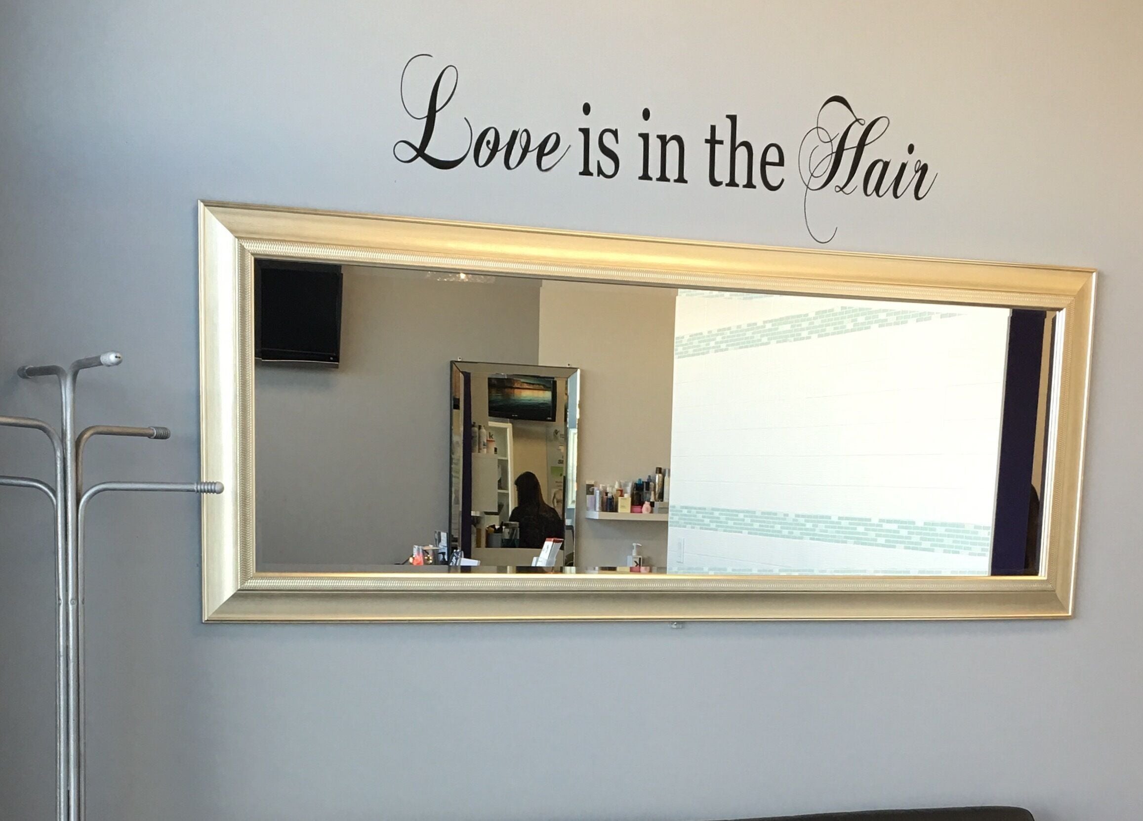 Elegant wall mirror at Si Salon and Spa in Edmonton, Alberta, CA with a 'Love is in the Hair' decal.