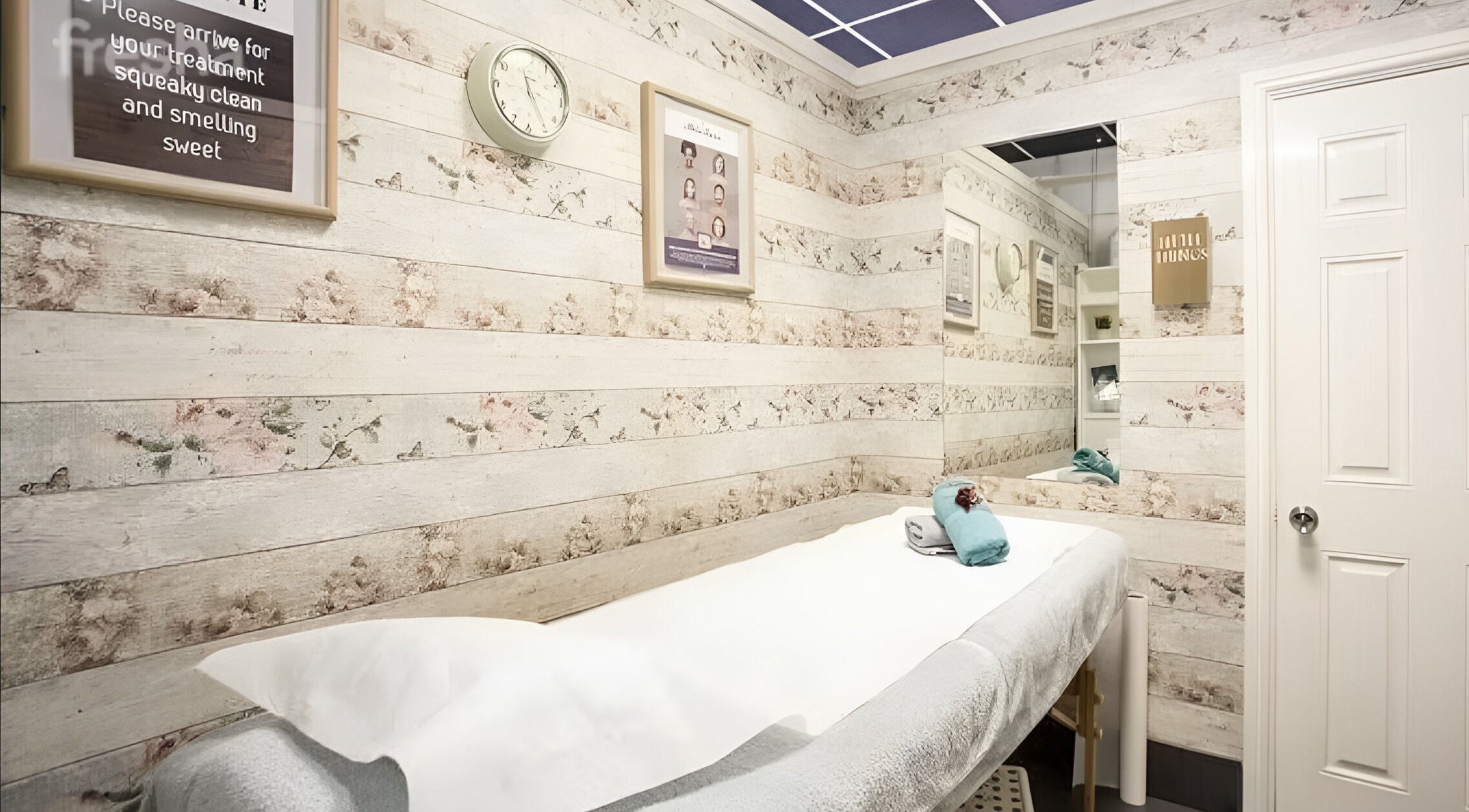 Tranquil treatment room at Fake It, Manchester, England, GB with floral decor and massage bed.