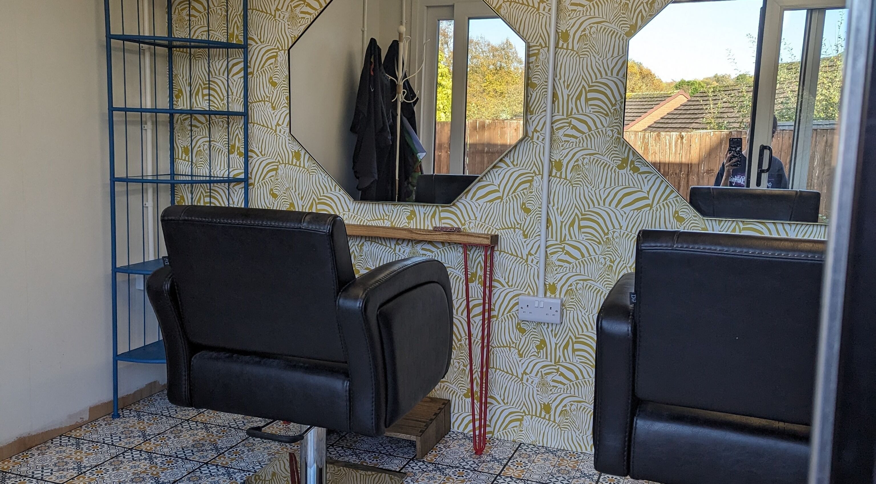 Chic salon setup at The Hair Lounge, Halesowen, United Kingdom, GB with modern chairs and patterned wallpaper.