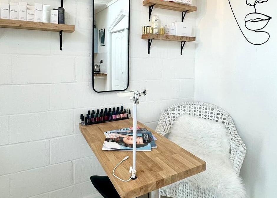 Chic treatment corner at Facial Attraction in London, England, GB; wooden desk, wicker chair, beauty products.