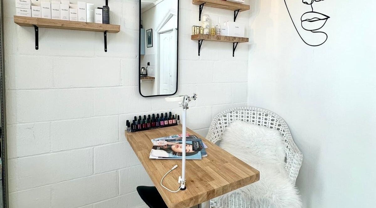 Chic treatment corner at Facial Attraction in London, England, GB; wooden desk, wicker chair, beauty products.