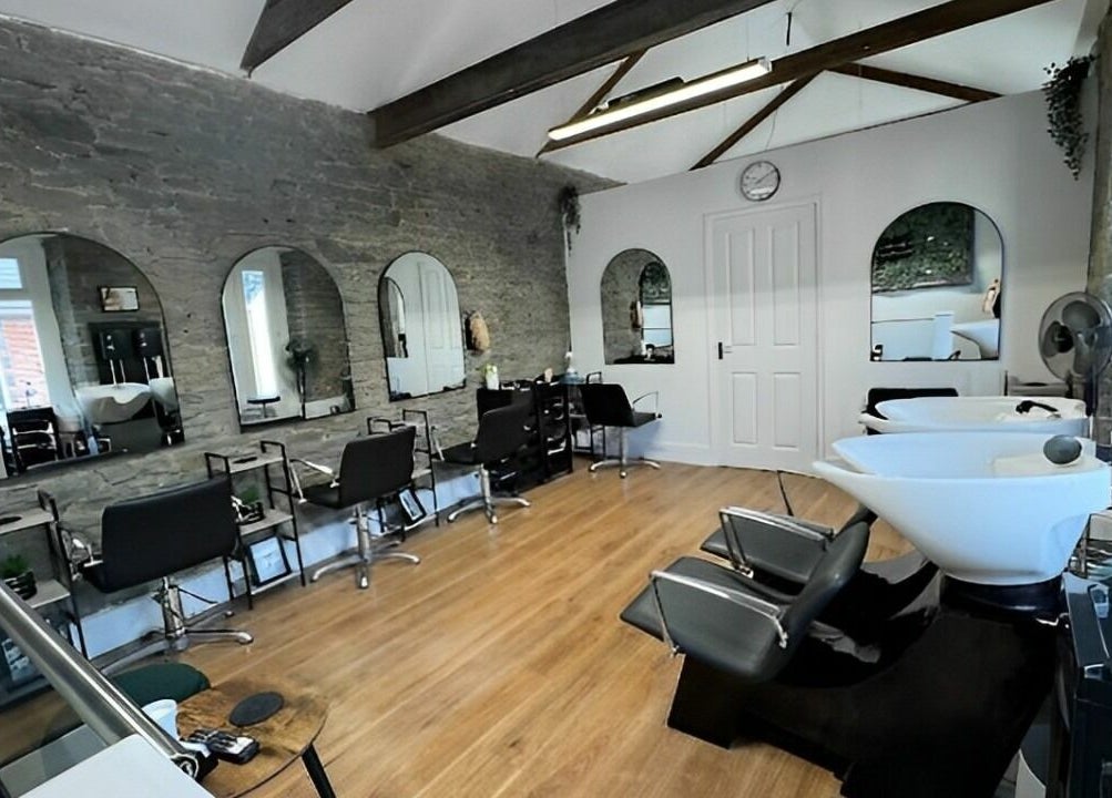 Spacious, modern interior of The Glow Studio Beauty Salon in Neath, Wales, GB with sleek styling chairs and mirrors.