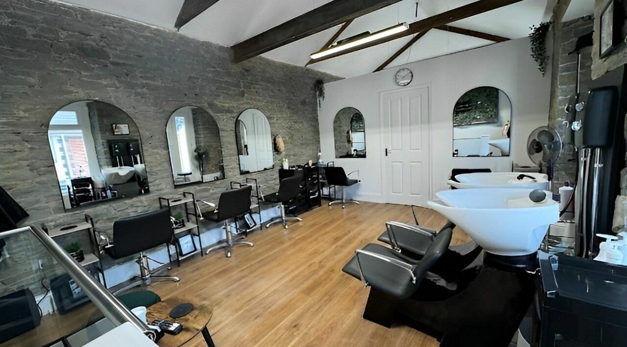 Spacious, modern interior of The Glow Studio Beauty Salon in Neath, Wales, GB with sleek styling chairs and mirrors.