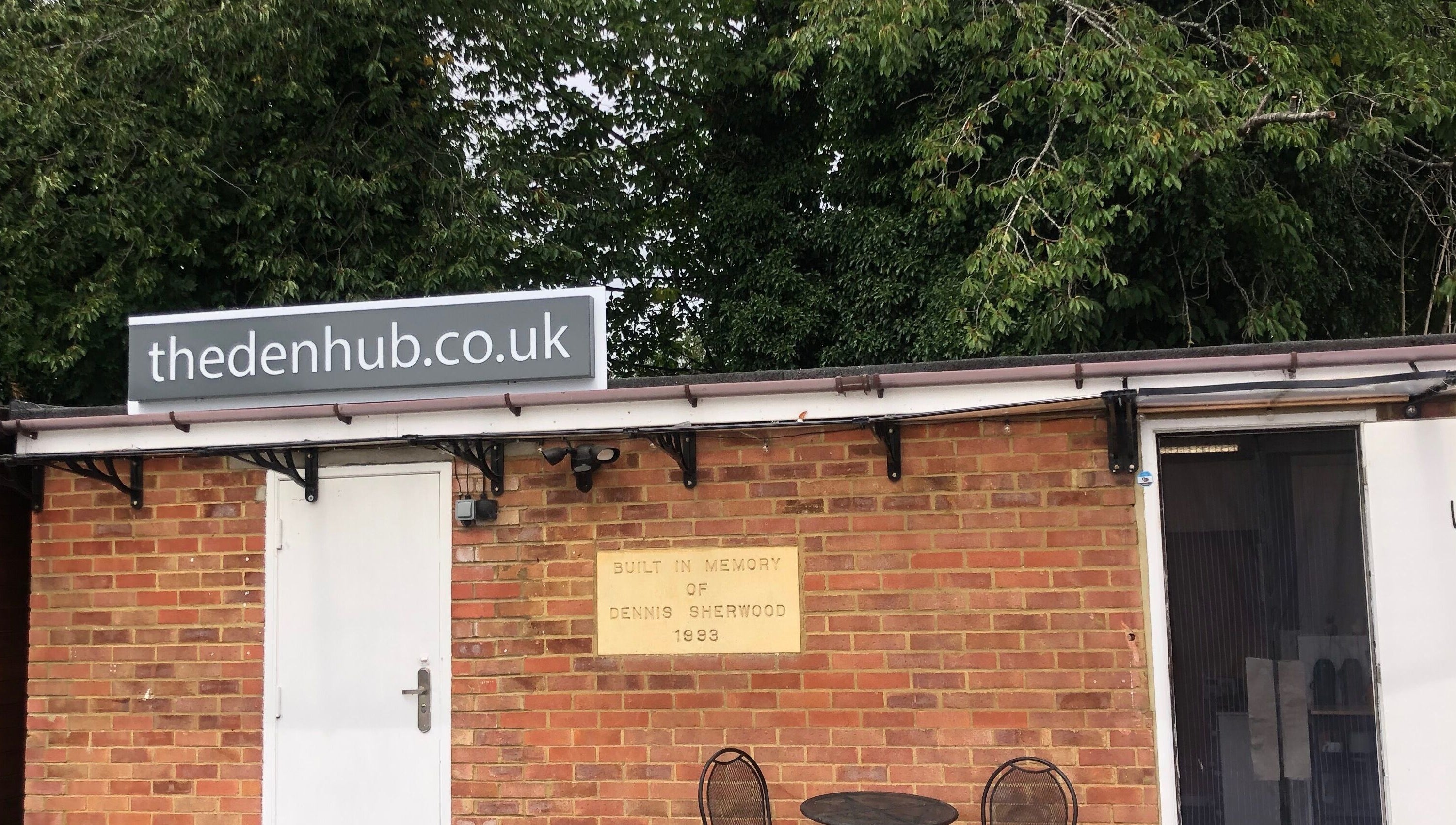 The Beauty Den entrance in Baldock, England, GB with a charming brick facade and greenery.