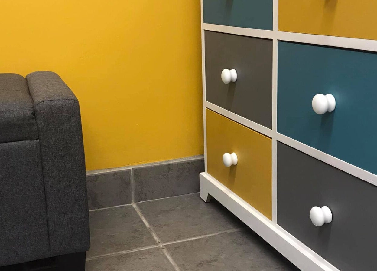 Stylish gray sofa and colorful drawers at The Beauty Den, Baldock, England, GB.