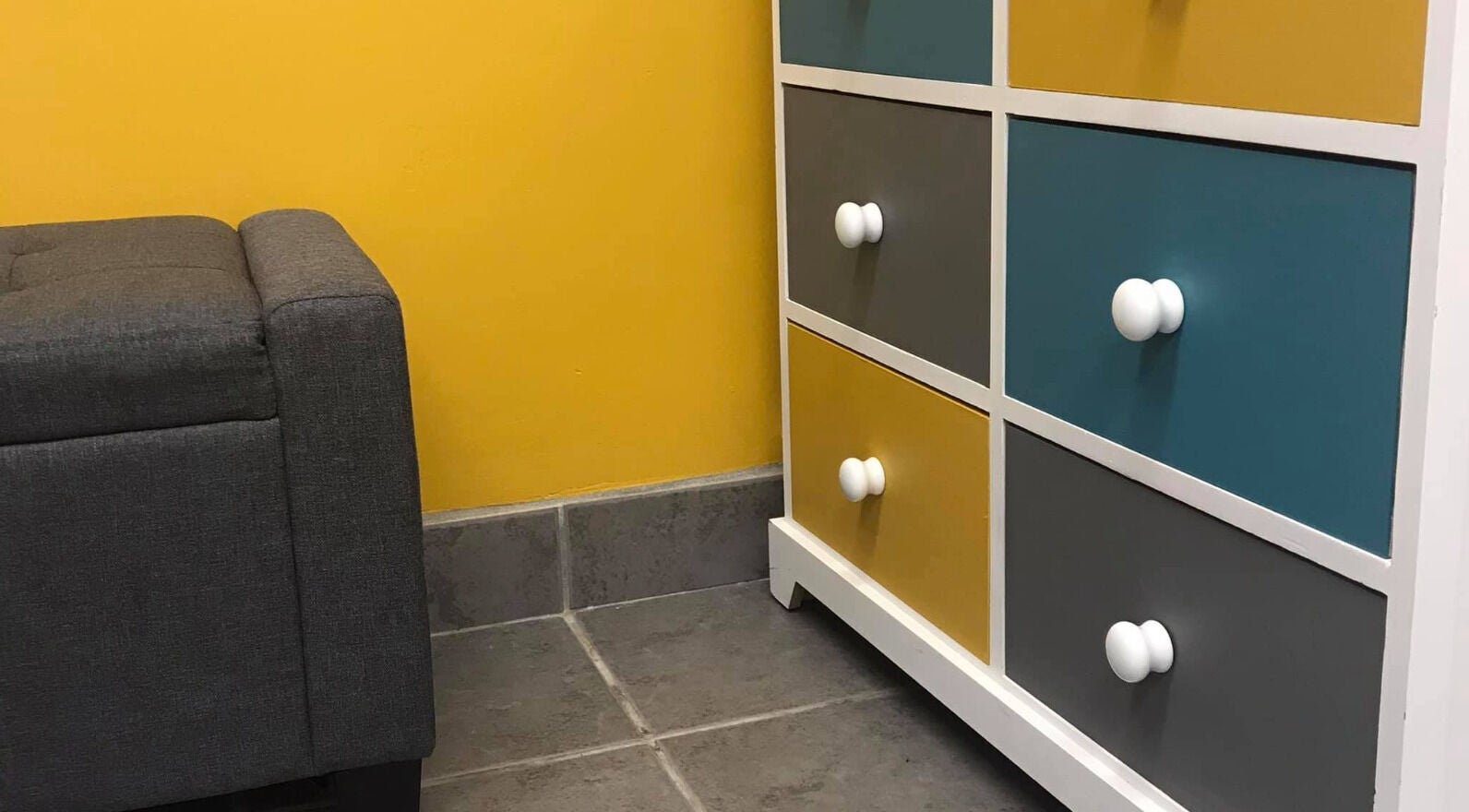Stylish gray sofa and colorful drawers at The Beauty Den, Baldock, England, GB.