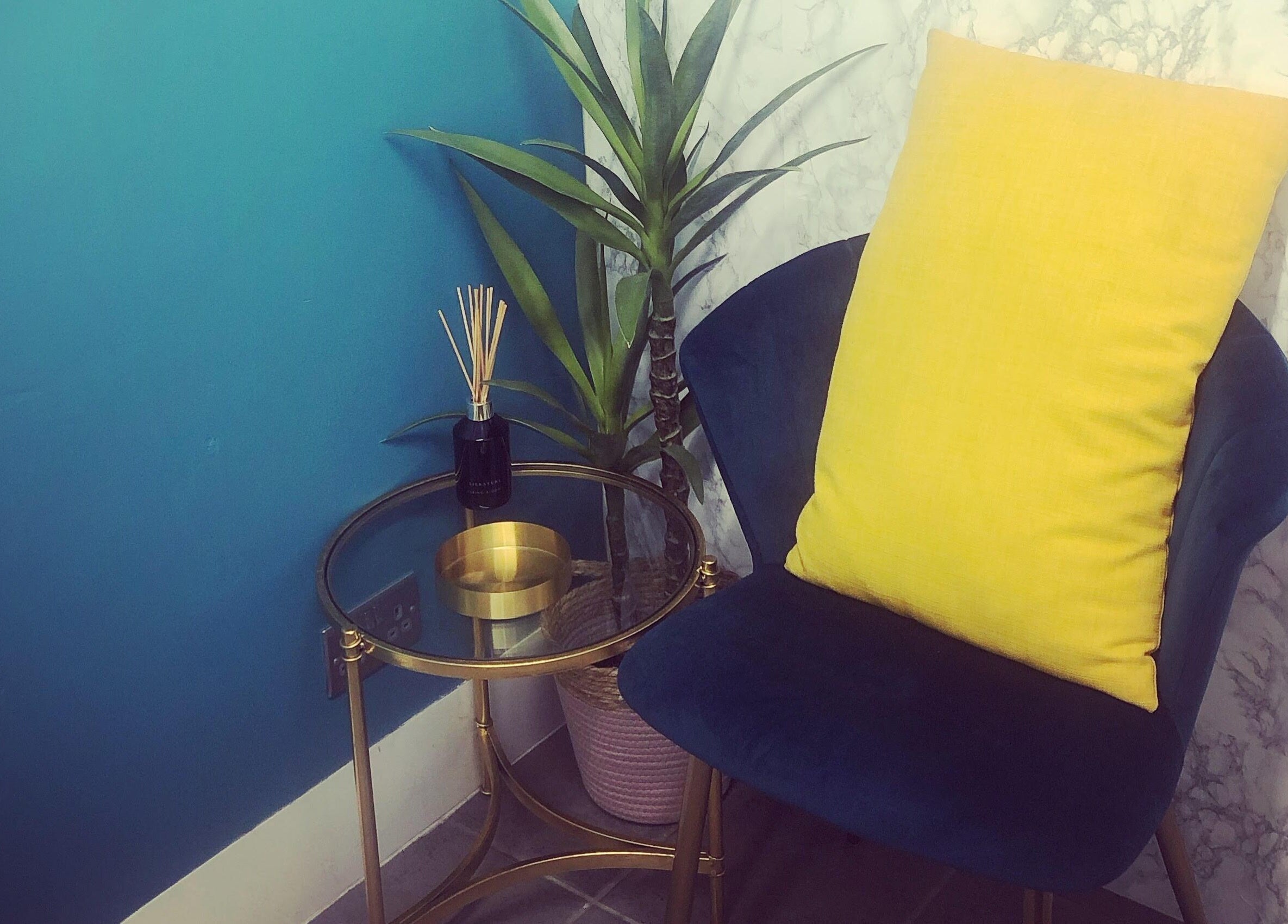 Chic seating area at The Beauty Den, Baldock, England, GB, featuring a blue chair and yellow cushion.