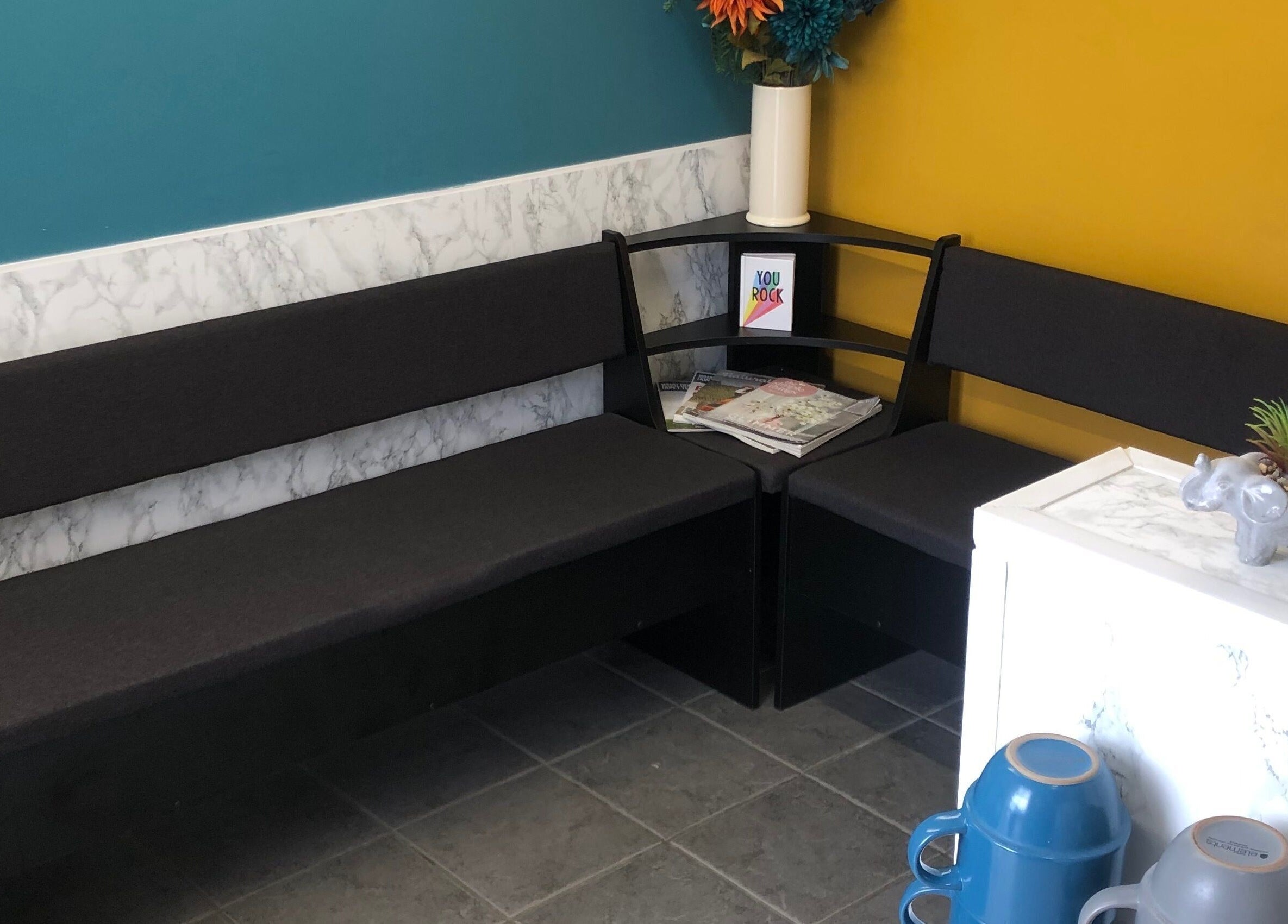 Inviting waiting area at The Beauty Den, Baldock, England, GB with dark benches and floral decor.
