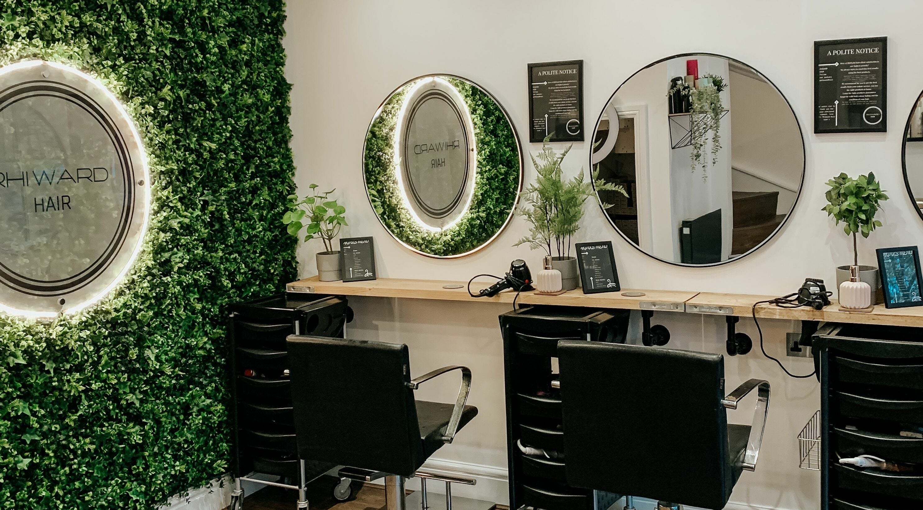 Elegant salon interior at RhiWard Hair in Rochdale, England, GB with lush greenery and stylish mirrors.