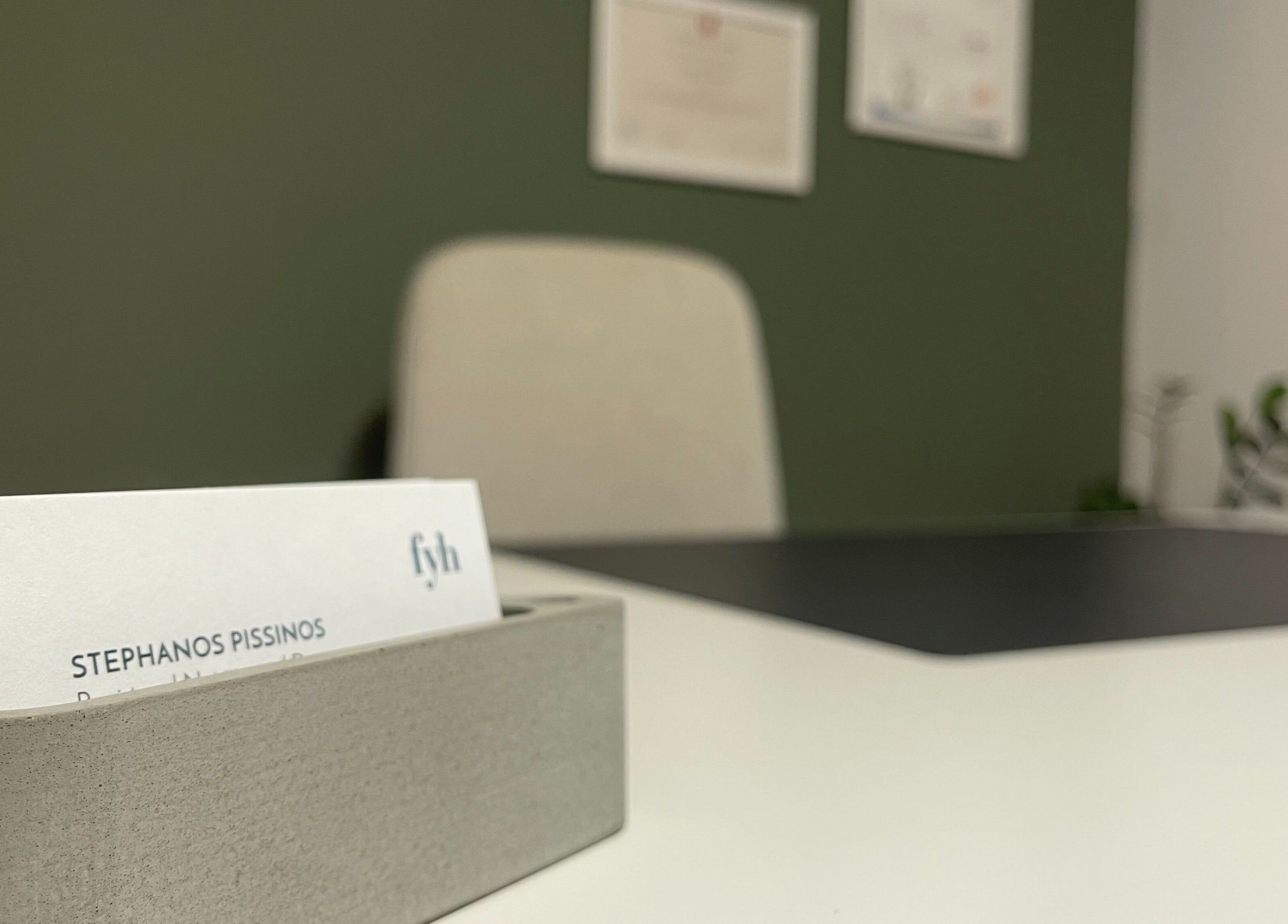 Modern office desk at Feed your Health, Aglantzia, Nicosia, CY, featuring business cards and a sleek chair.