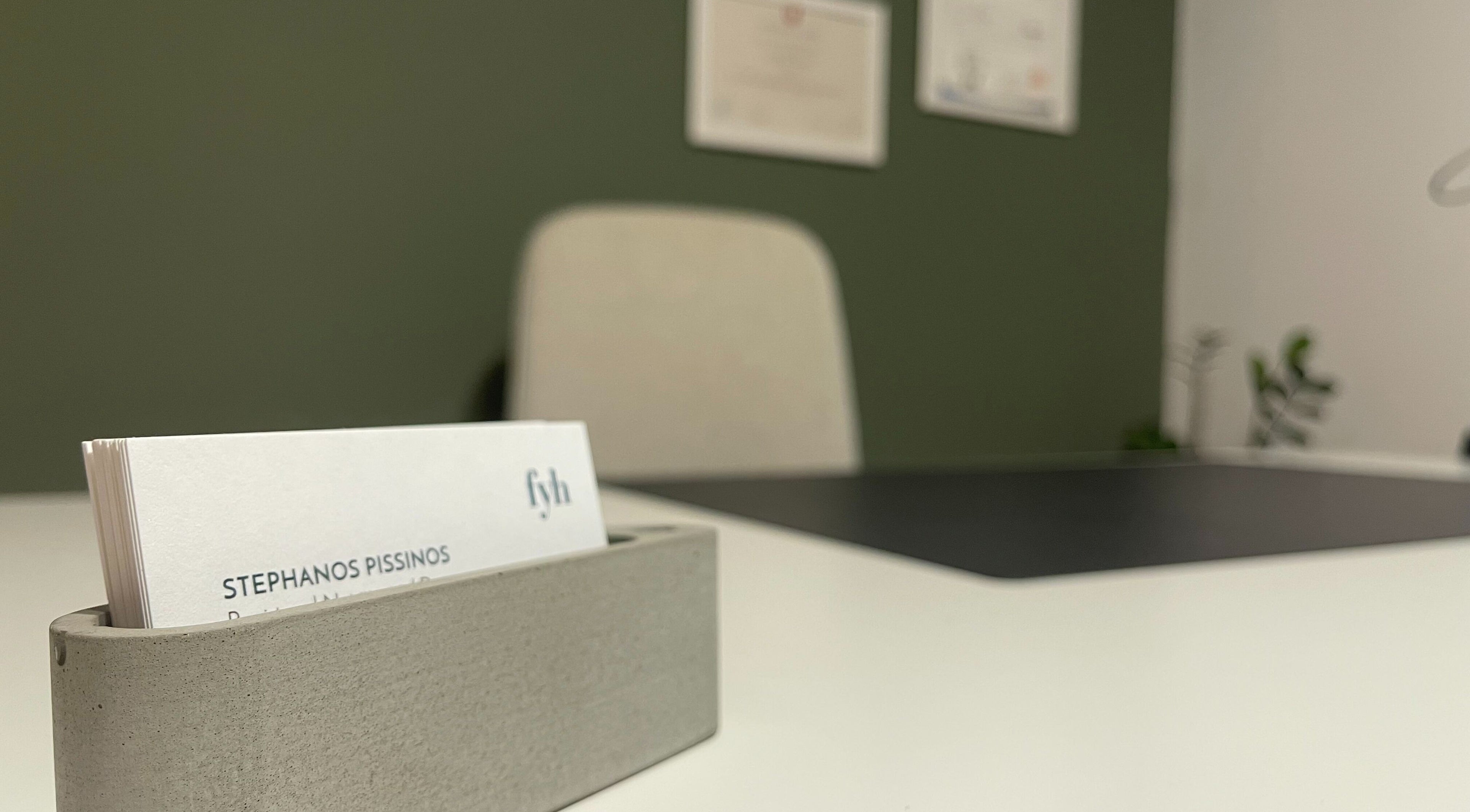 Modern office desk at Feed your Health, Aglantzia, Nicosia, CY, featuring business cards and a sleek chair.