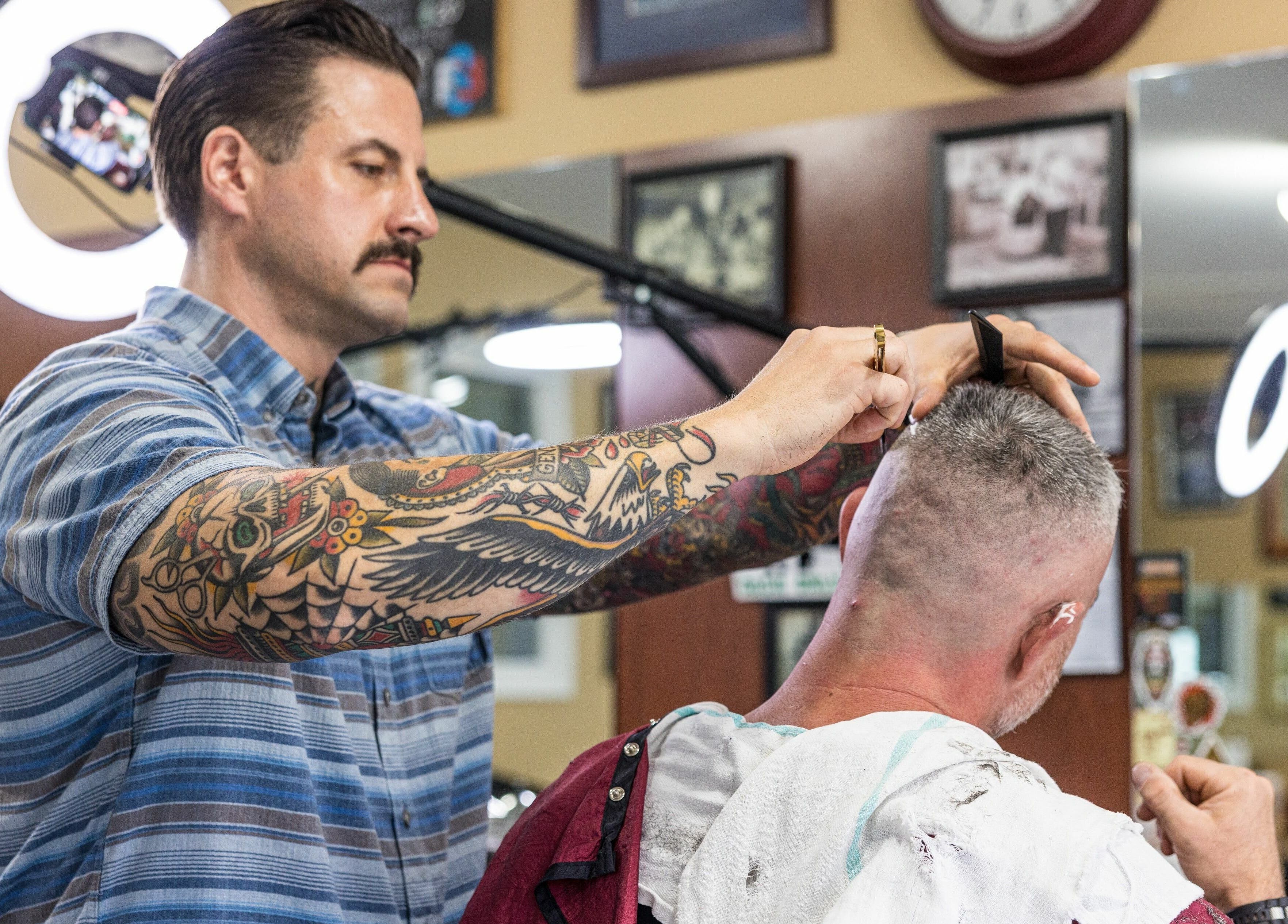 Barber at Empire State Barbershop in Tappan, New York, US expertly cutting a client's hair.