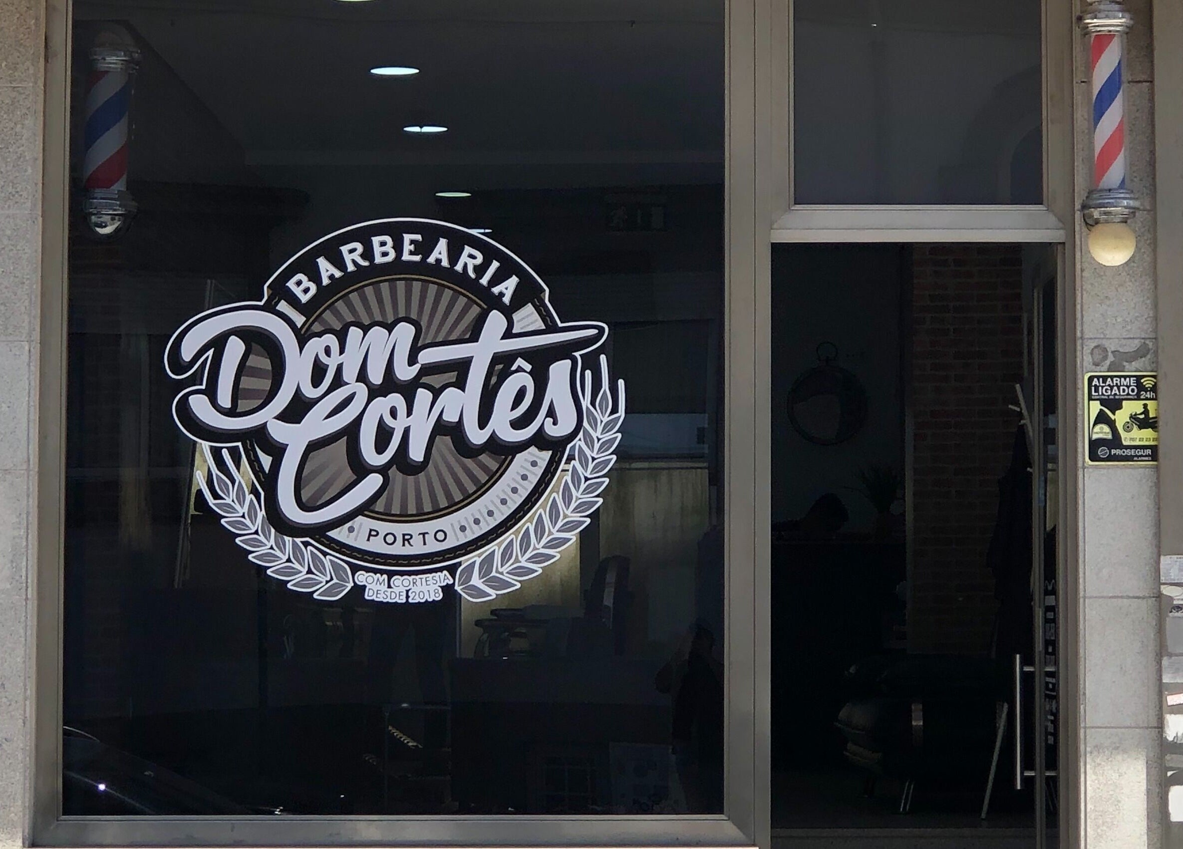 Entrada da Barbearia Dom Cortês em Porto, Porto, PT, destacando o logotipo estilizado.