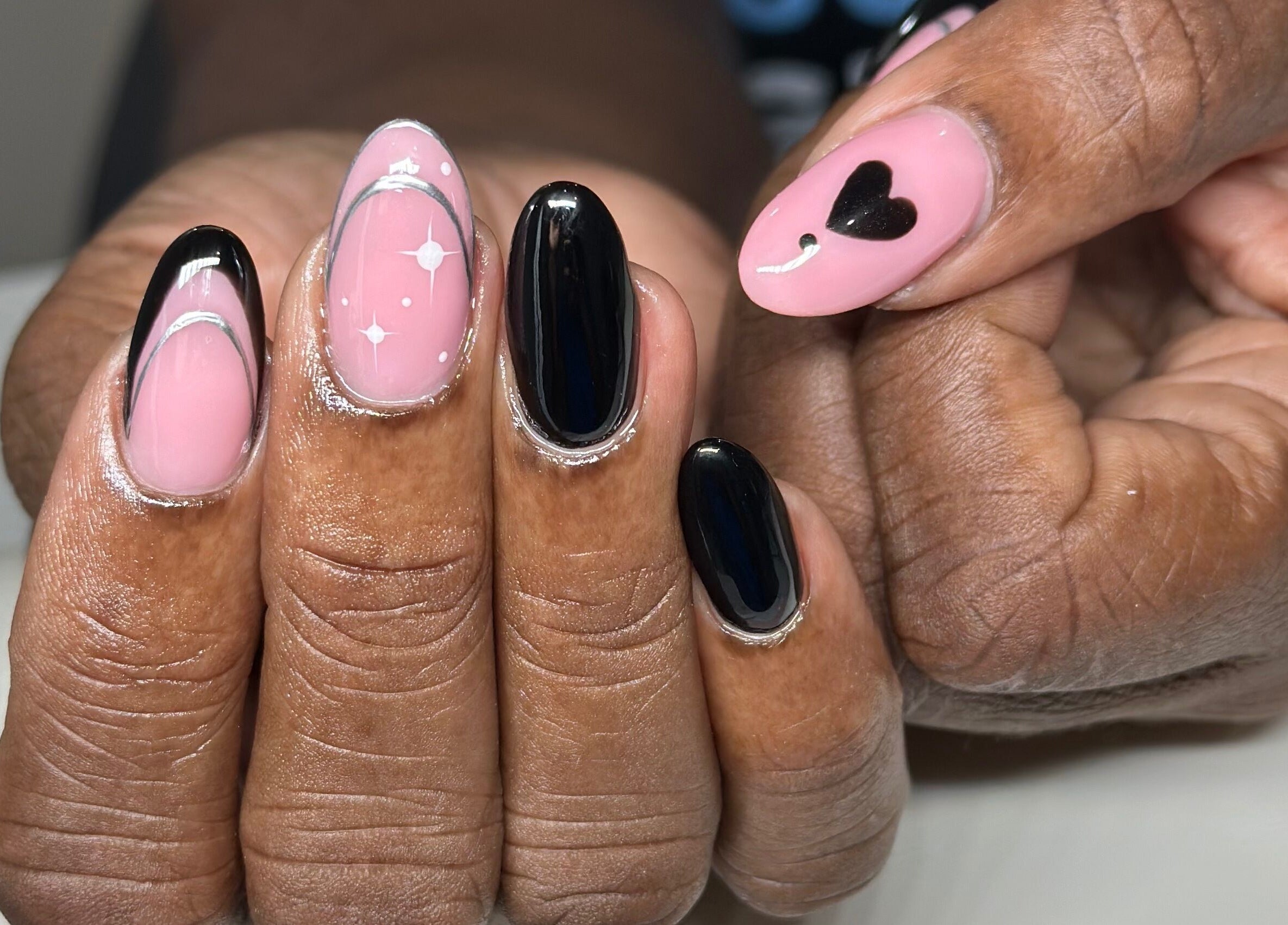 Nhanced in Bridgetown, Saint Thomas, BB features intricate black and pink nail art with heart and star designs.