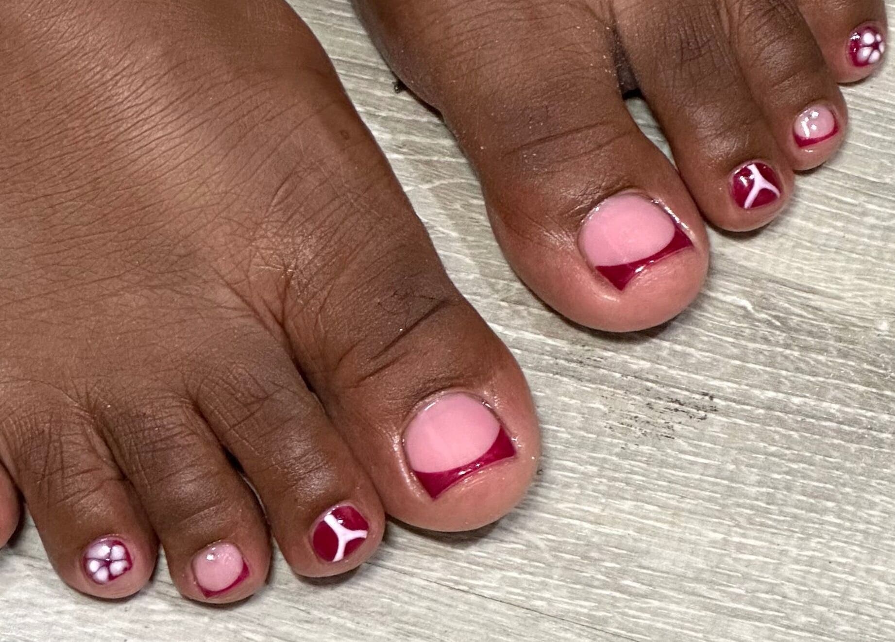 Stylish toenail art at Nhanced, Bridgetown, Saint Thomas, BB includes intricate red and pink designs.