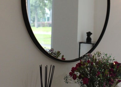 Elegant interior of SILKMUSE Laser & Skin in Uddingston, Scotland, featuring a round mirror and floral decor.