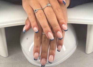 Blush beauty studio in Henfield, England, showcases elegant blue-tipped nails on a white table.