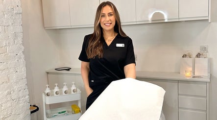 Expert at RS Artistry, Dronfield, England, GB, standing by treatment table in a serene, modern setting.