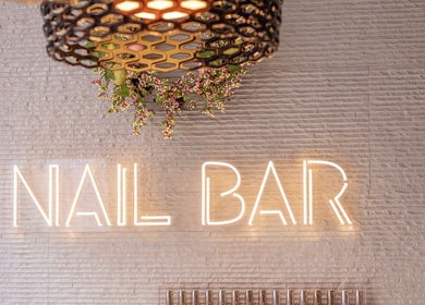 Neon lit 'Nail Bar' at Mayfair Aesthetics and Beauty, London, England, GB. Modern decor with floral accents.
