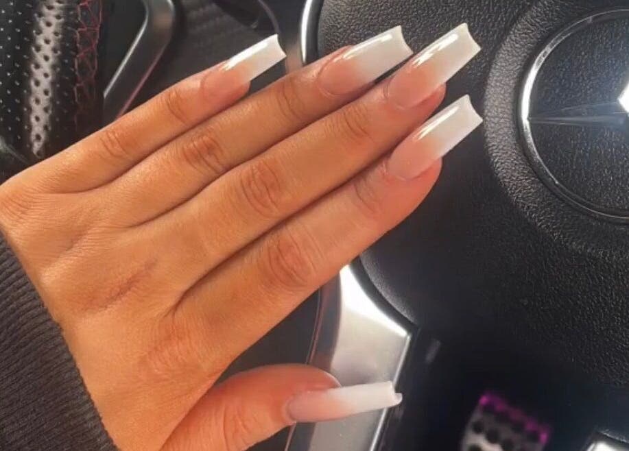 Stylish manicured nails at House of Rome, Beckingham, England, GB on a car steering wheel.