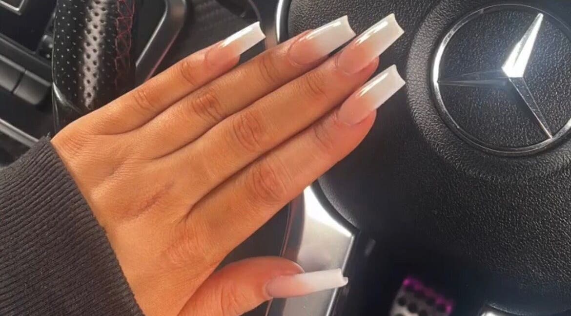 Stylish manicured nails at House of Rome, Beckingham, England, GB on a car steering wheel.