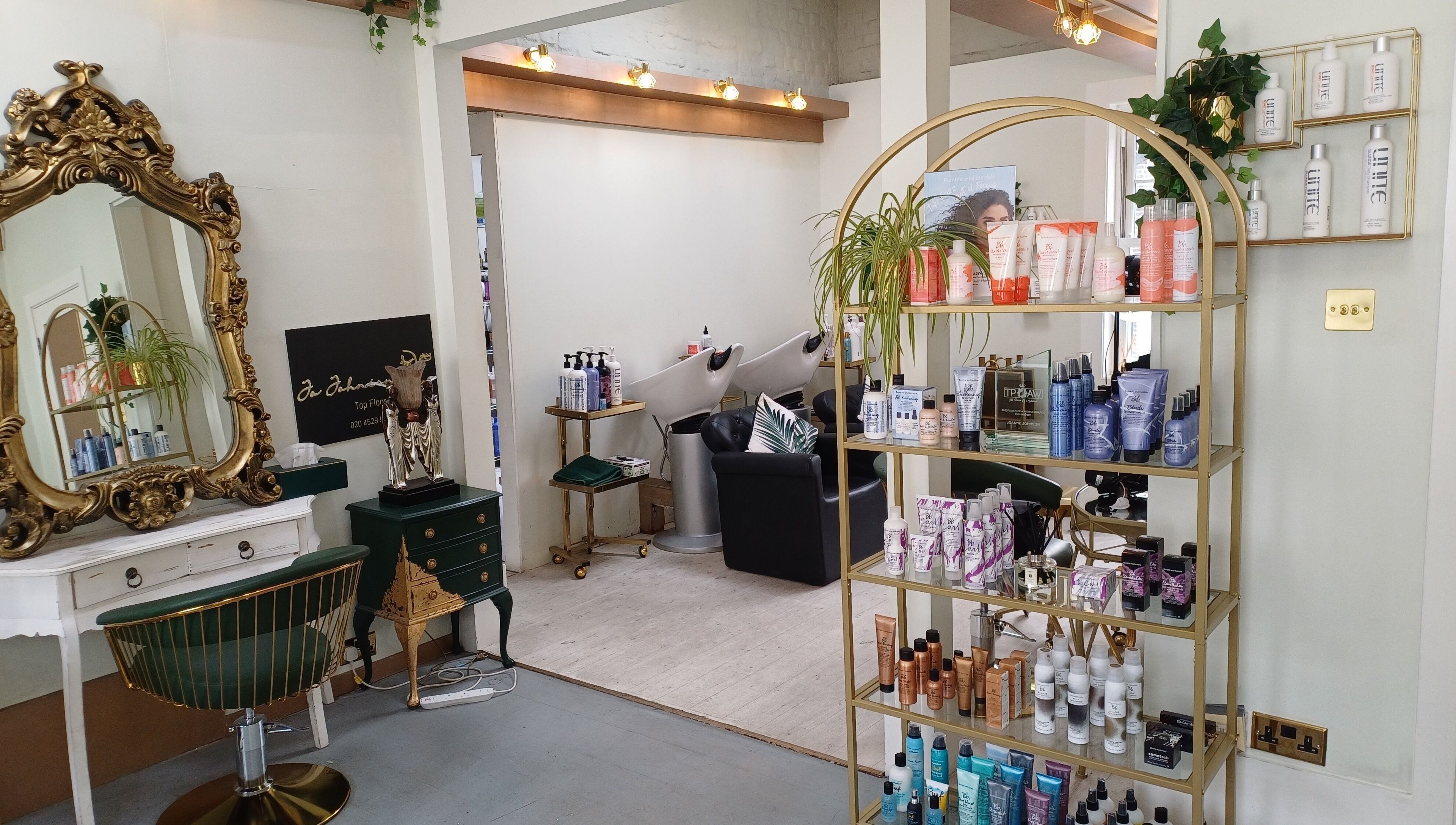 Elegant interior of Jo Johnson Salon in London, England, GB, featuring a gold mirror and stylish product display.