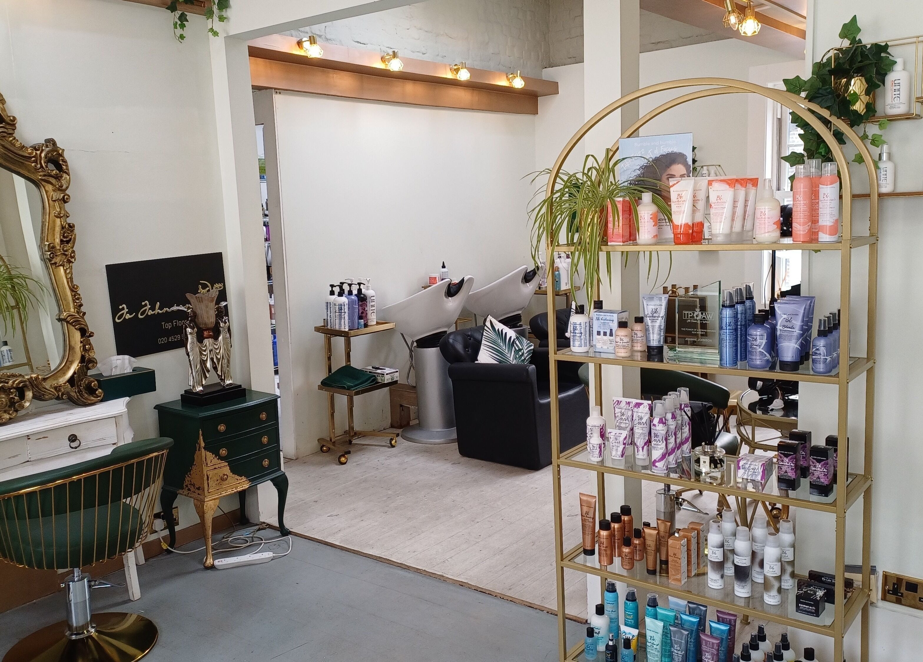Elegant interior of Jo Johnson Salon in London, England, GB, featuring a gold mirror and stylish product display.