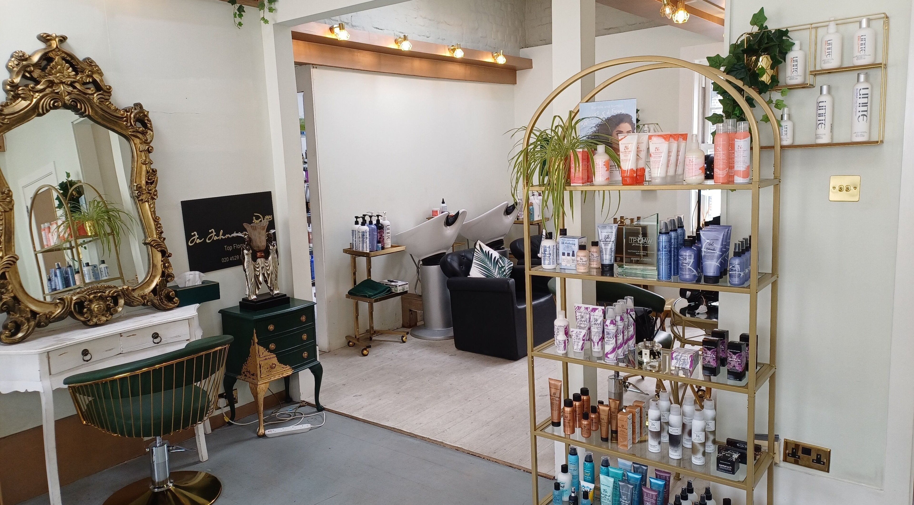 Elegant interior of Jo Johnson Salon in London, England, GB, featuring a gold mirror and stylish product display.